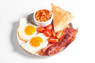 Delicious traditional English breakfast with fried eggs, beans, bacon, tomatoes and toasts