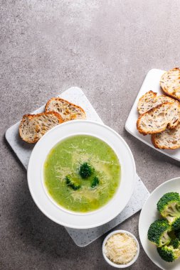 Sıcak ve rahatlatıcı kremalı brokoli çorbası bir kasede servis edilir, parmesan peyniri ve kızarmış ekmekle süslenir..