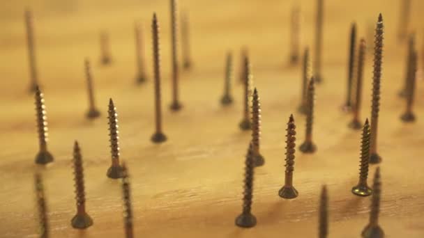 Dozens of metal screws standing on end, hand selectively moves some, close up slide right — Stock Video