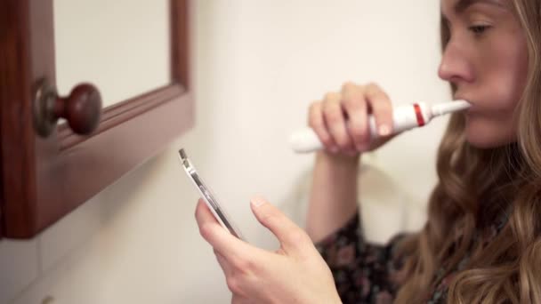 女人们在浴室刷牙的时候看智能手机，关上门 — 图库视频影像