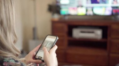 Kız hızlı bir şekilde sosyal medyada akıllı telefondan görüntü alıyor, TV ekranı görüntüde