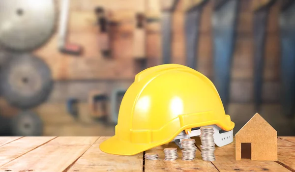 Casco de seguridad capataz y moneda en una mesa de madera —  Fotos de Stock