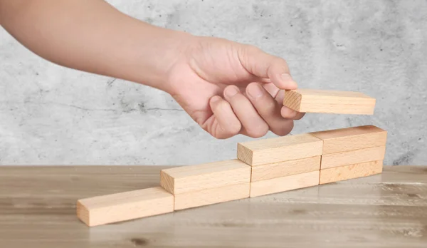 Hand liken person stepping up wood block stacking as step stair