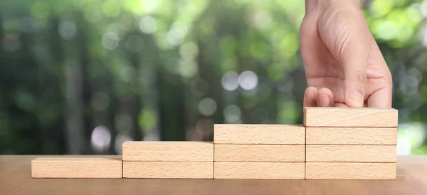 Hand arranging a wood block stacking as step stair, Business concept growth success process