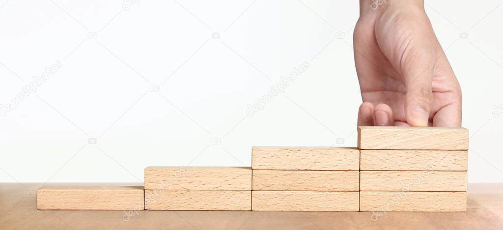 Hand arranging a wood block stacking as step stair, Business concept growth success process