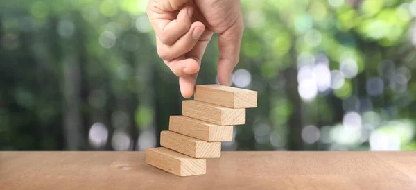 Hand arranging a wood block stacking as step stair, Business concept growth success process