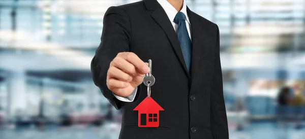 Real estate agent handing over house keys in hand