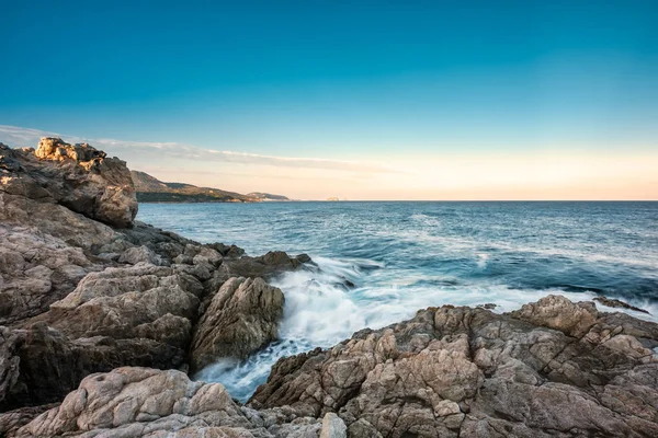 波距離イルルッス夜明け改として Lozari でコルシカ島の岩の多い海岸に洗濯 — ストック写真