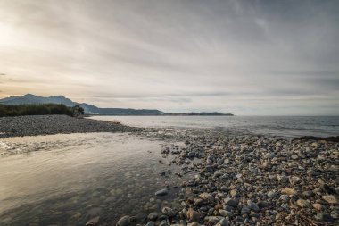Sığ bir nehir Akdeniz'e Calvi uzaktan Kalesi ile Corsica'deki / daki bir çakıl plajında katıldı