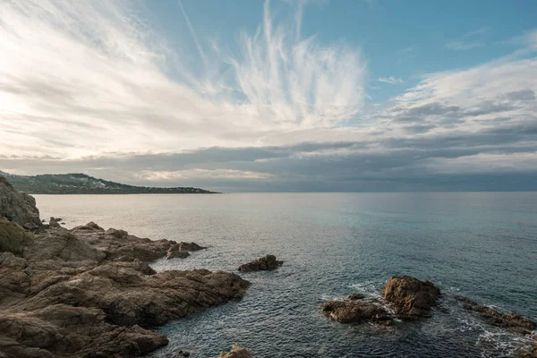 コルシカ島の遮へい Balagne 領域で岩の多い海岸線が沈む太陽としてうっすら夜雲 — ストック写真
