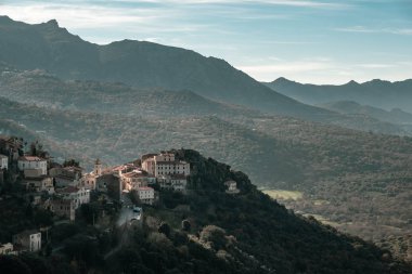 Öğleden sonra güneş ışığında Corsica Hills Balagne bölgesinin Belgodere antik dağ köyü ve mesafe dağlarda