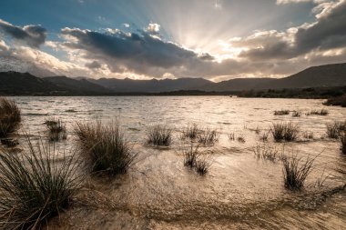 Lac de Codole Corsica Balagne bölgede kar ile Regino Vadisi üzerinde bulutlar arkasında güneş ayarı mesafe dağlarda şapkalı