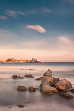L'Ile Rousse, Corsica - 5 Şubat 2019. Korsika Linea feribot gündoğumu Corsica Balagne bölgesinin L'Ile Rousse bağlantı noktası, bekler. Uzun pozlama görüntü ön planda taşlarla.
