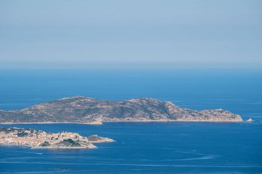 Korsika 'nın Balagne bölgesinde antik Calvi Kalesi. Etrafı mavi Akdeniz ile çevrili ve arkasında Revellata var.