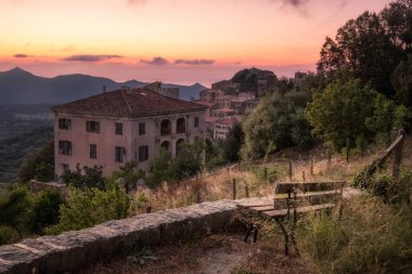 Korsika 'nın Balagne bölgesindeki Belgodere antik dağ köyünün üzerinde gün batımını gören eski bir bank.