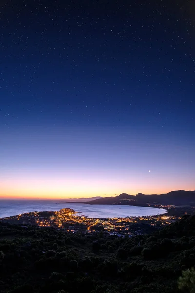 三日月は丘の中腹の村のライトとコルシカ島のバルーン地域のカルヴィの湾と要塞の上に明確な星空の夜に夜明けに上昇し キャップコルセ遠くに見える — ストック写真