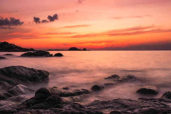 ルセの赤い岩ラ ピエトラの上の日没 地中海の波が前景の岩の海岸線を突き破ってコルシカ島のバルーン地方 — ストック写真