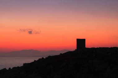 Korsika 'nın Balagne bölgesindeki Lumio yakınlarında Punta Spano' daki siluetli Ceneviz kulesinin üzerinde şafak söküyor.