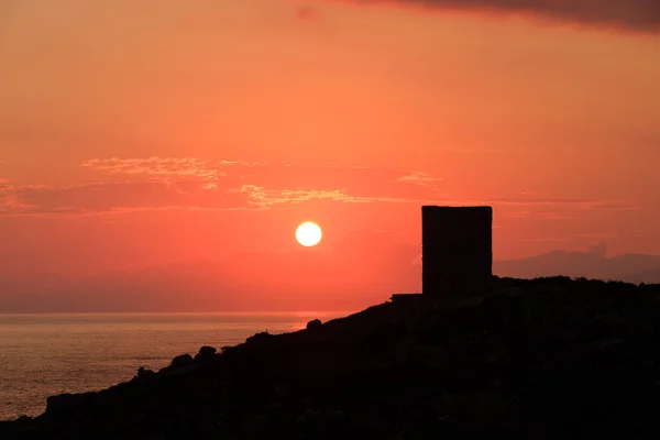 太陽は遠くにキャップコースとコルシカ島のBalagne地域のLumio近くのプンタ スパノのシルエットのジェノヴァの塔の後ろに立ち上がります — ストック写真