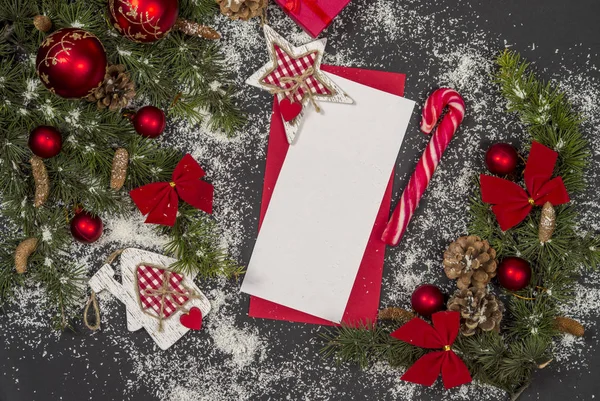 Winter frame: christmas decoration surrounding red envelope on black background