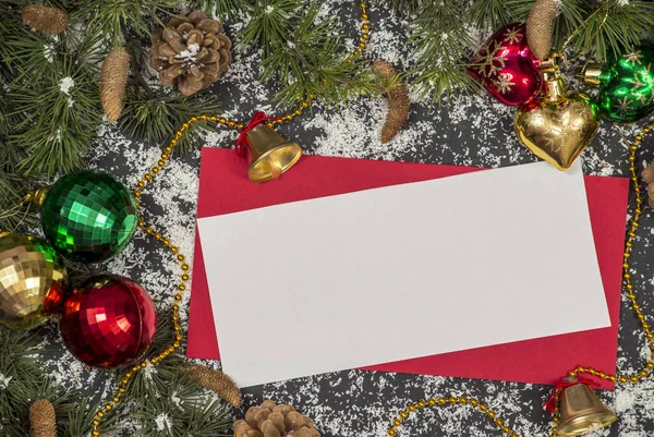 Winter frame: christmas decoration surrounding red envelope on black background