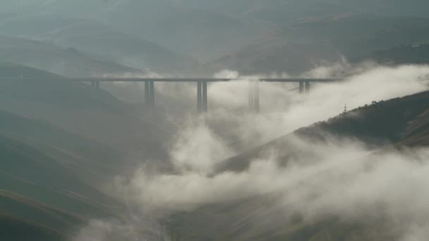 雲の上の映画8K 7680X4320 Highway Bridge屋根付きの霧と雲の下の谷 車の交差道路霧対流曇り水蒸気の湿度濃度現在の霧の冬の太陽の丘の秋の地形霧のビュー地上湿った — ストック動画
