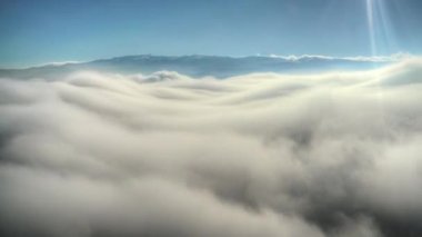 Sinematik 8K 7680x4320.Yüzeyde kara coğrafyasında sis. Dağ zirvesinden yükselen bulutların üzerinde. Geniş bir manzara bulutu. Stratusdan bir sis denizi oluştu. Sis bulutu..