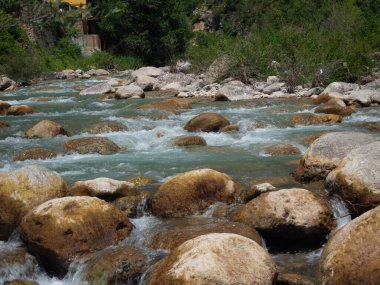 Dağdaki taşların arasından akan suyu oluşturan kıllı bir manzara.