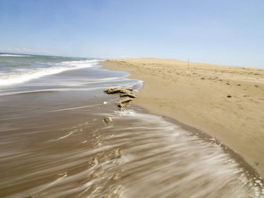 Güneşli bir günde deniz dalgaları ve kum.