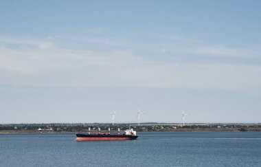 Rüzgâr değirmenlerinin önündeki ticari nakliye gemisi. Deniz kargo gemisi. Deniz aşırı lojistik ve nakliye hizmetleri