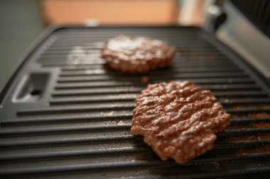 Elektrikli ızgarada yenmeye hazır iki domuz burger köftesi. Tasarım modeli için kopyalama alanı. Kızarmış et ürünü