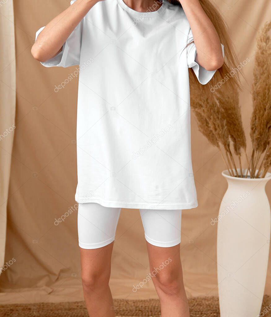 young fit girl wears oversized white t shirt with white legging shorts. copy space street wear mock up
