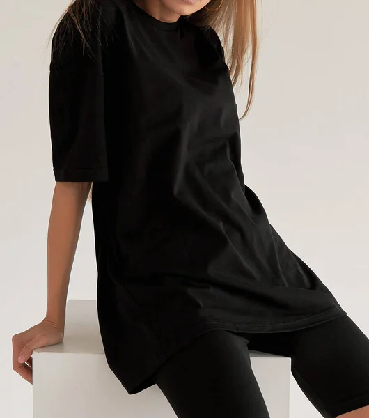 woman wears oversize black shirt and black shirt. dark streetwear outfit young girl