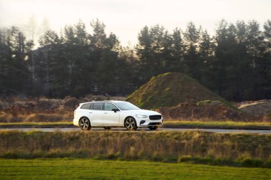 Kırsal alanda dolaşan beyaz elektrikli araba.