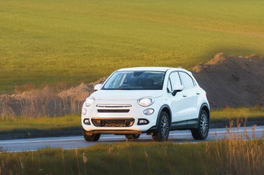 Açık kırsal yolda ilerleyen küçük bir şehir arabası.