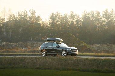 Çatı kutusu açık yolda giden bir SUV.