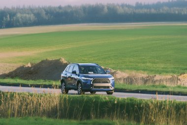 Çerçevede sert bir cip var. Kırsal alanda geziniyor.