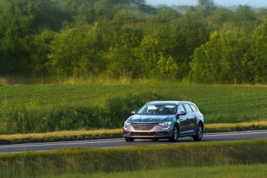 Wagon vehicle cruising past lush green scenery