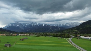 Kırsal kabinleri ve Alpleri olan yemyeşil bir alan.