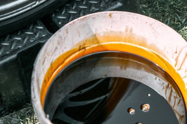 İçinde koyu renkli motor yağı kullanılmış beyaz konteynır