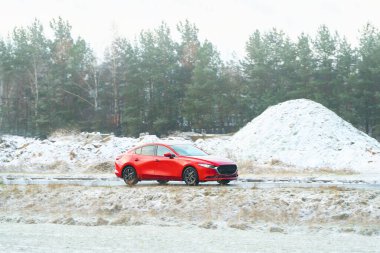 Parlak kırmızı otomobil kırsal alanda seyahat ediyor.