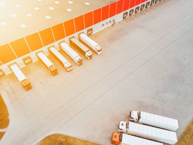 Depo, park halindeki nakliye kamyonlarıyla yükleme yapıyor.