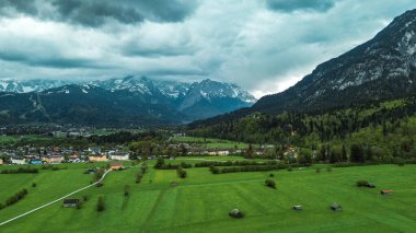 Yeşil manzaralı köyün üzerinde kar kaplı Alpler