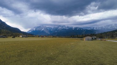 Kırsal kabinleri ve Alpleri olan yemyeşil bir alan.