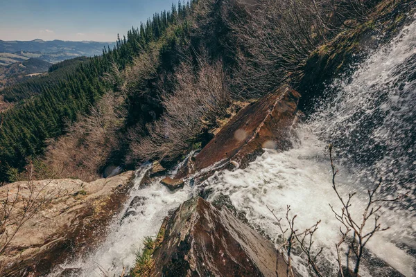 Uma cachoeira com árvores ao lado de uma montanha — Fotografia de Stock