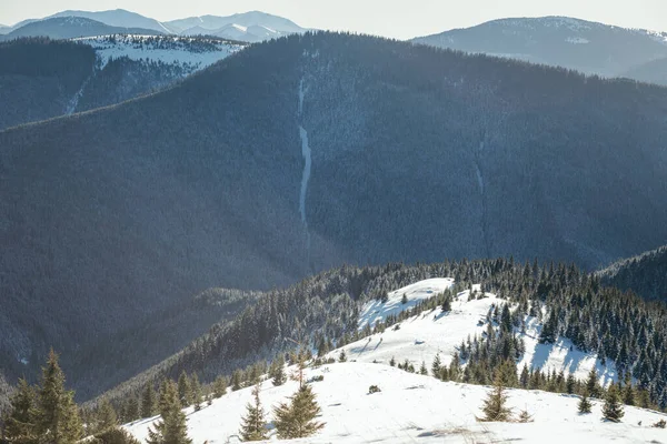 Um homem montando um snowboard abaixo de uma montanha coberta de neve — Fotografia de Stock