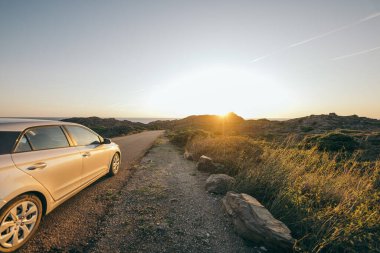 Kirli arazinin kenarına park etmiş bir araba.