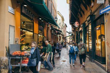Bir grup insan bir mağazanın önündeki kaldırımda yürüyorlar.