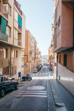 Binanın kenarında arabaların park ettiği dar bir şehir caddesi.