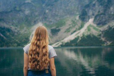 Bir su kütlesinin önünde duran biri.